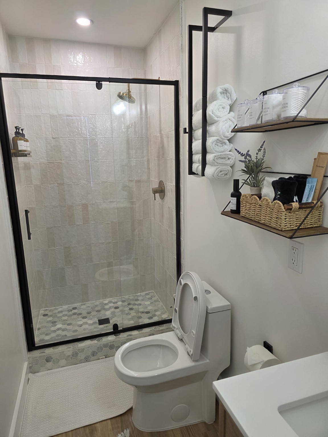 Bathroom with a glass shower enclosure, white tile and neatly arranged towels.