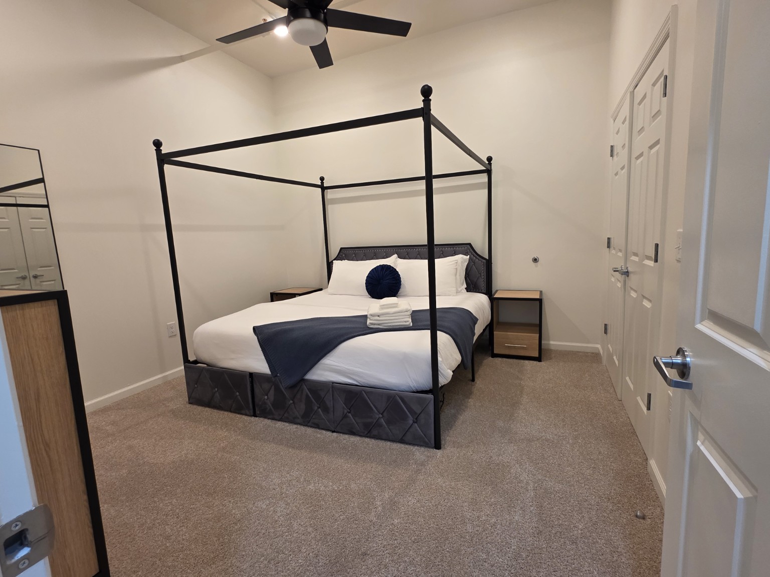 Guest bedroom with a four-poster bed, white linens and folded towels.
