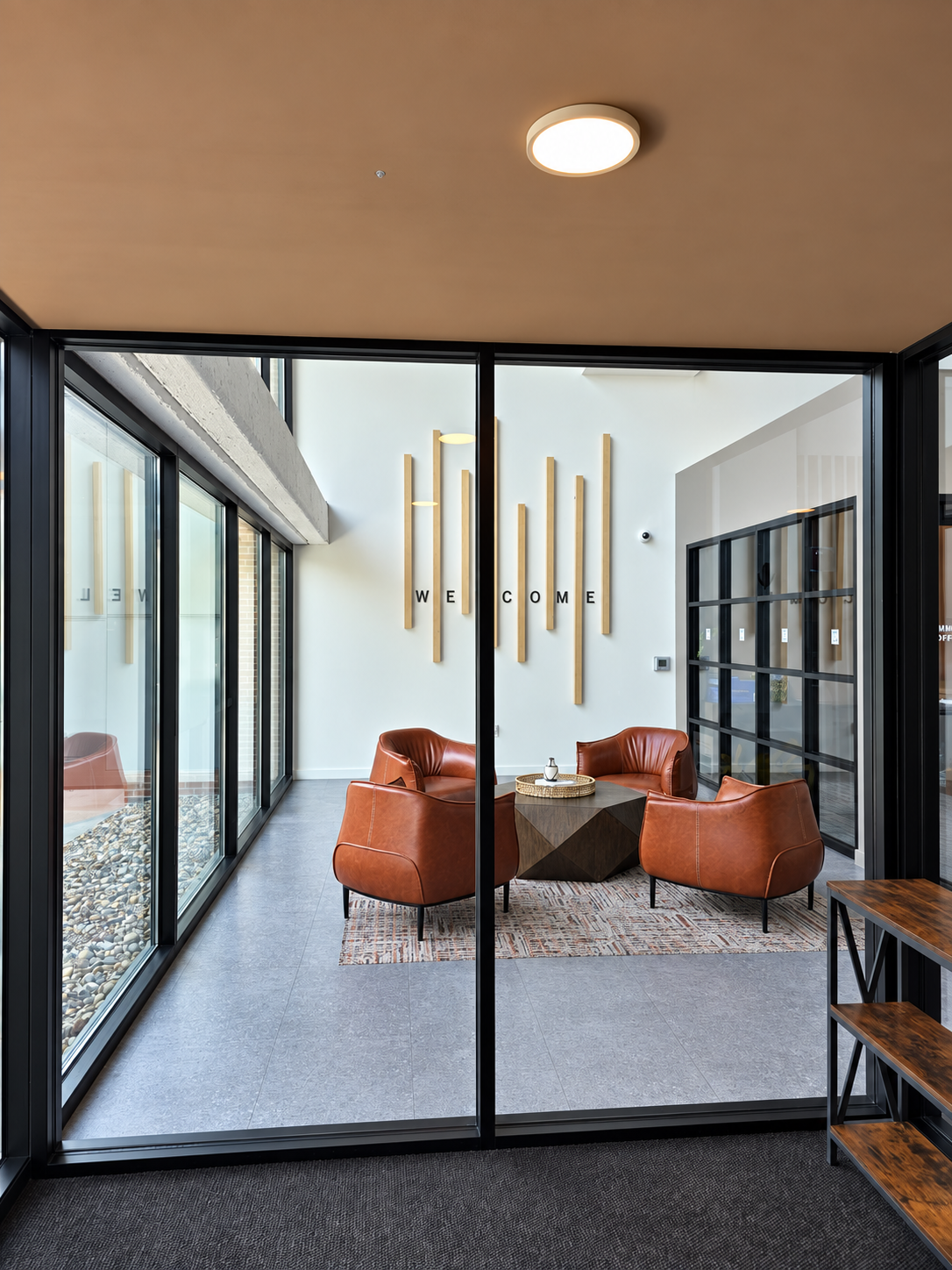 Lounge with leather chairs, a coffee table and glass partitions.