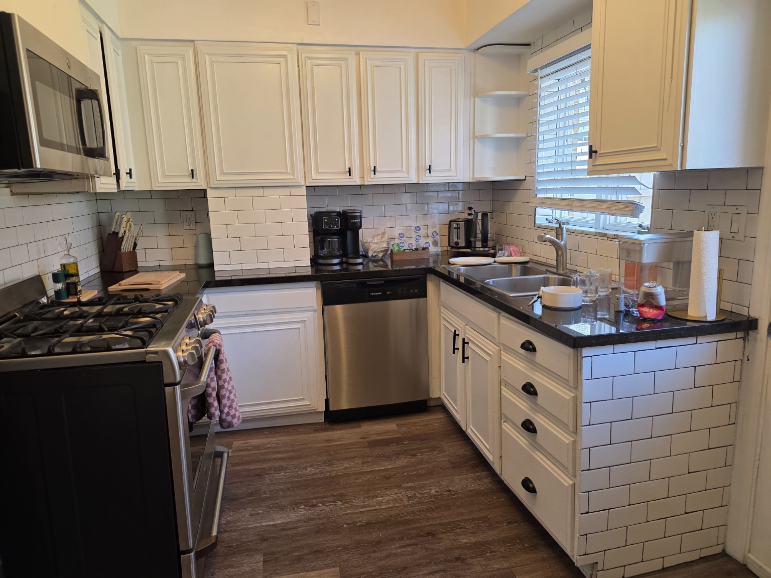 Kitchen with white cabinets, dark countertops and stainless steel appliances.